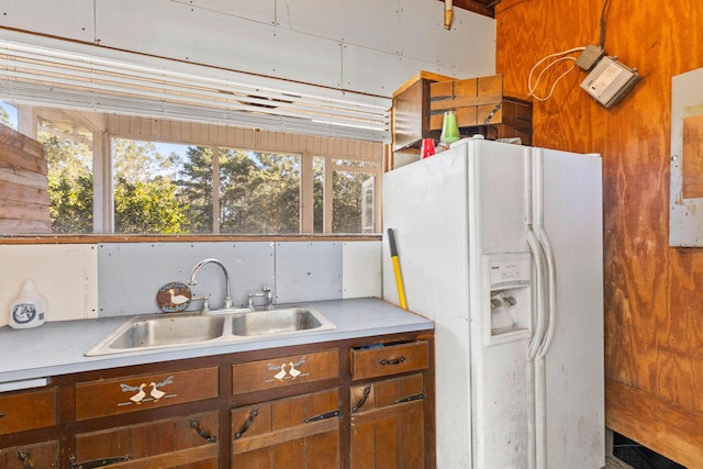 kitchen with a sink, light countertops, and white fridge with ice dispenser