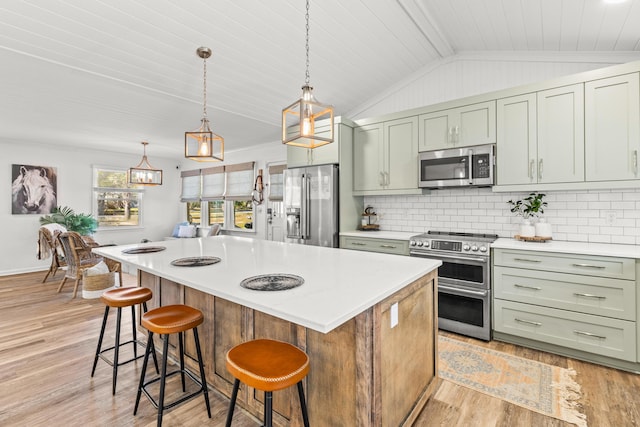 kitchen with backsplash, stainless steel appliances, light countertops, and vaulted ceiling