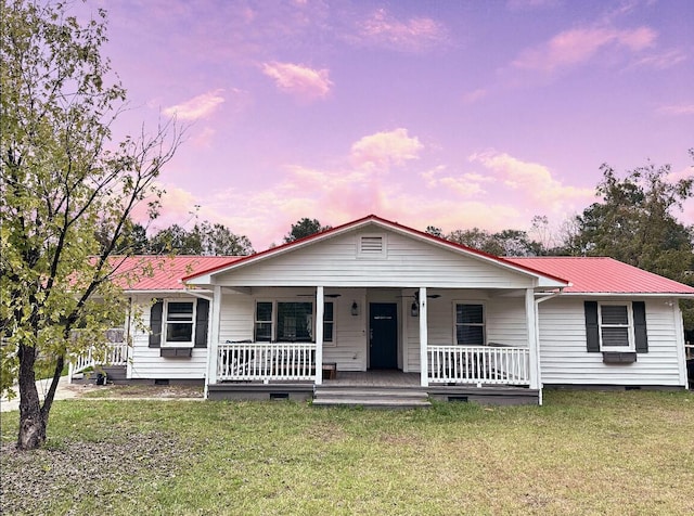 view of front of house with crawl space, a yard, a porch, and metal roof