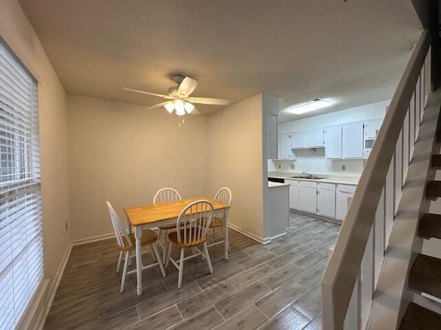 dining space with ceiling fan, sink, and a textured ceiling