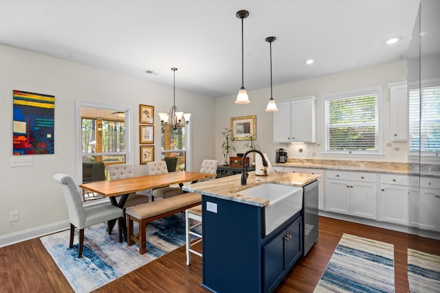 kitchen with a wealth of natural light, an inviting chandelier, white cabinetry, and a sink