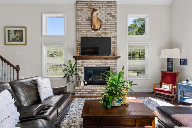 living room featuring a fireplace, a high ceiling, wood finished floors, stairs, and baseboards