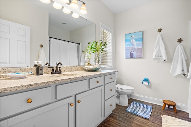 bathroom with toilet, baseboards, vanity, and wood finished floors