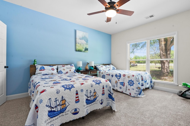 carpeted bedroom with visible vents, baseboards, and a ceiling fan