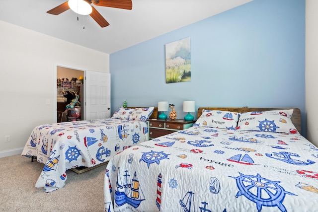 carpeted bedroom featuring baseboards, a walk in closet, a closet, and a ceiling fan