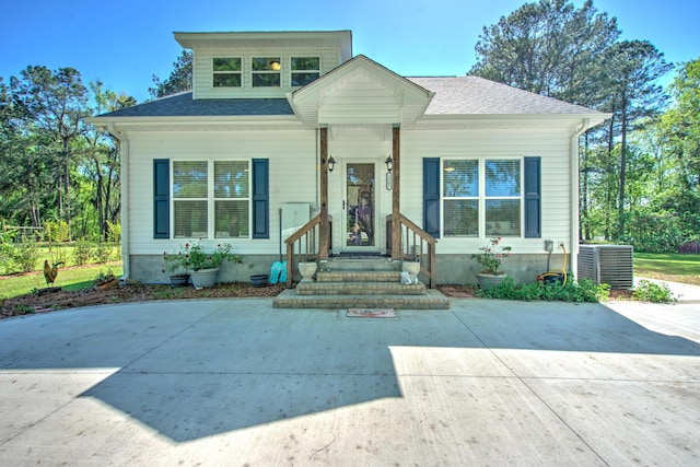 bungalow-style house featuring central AC and a shingled roof