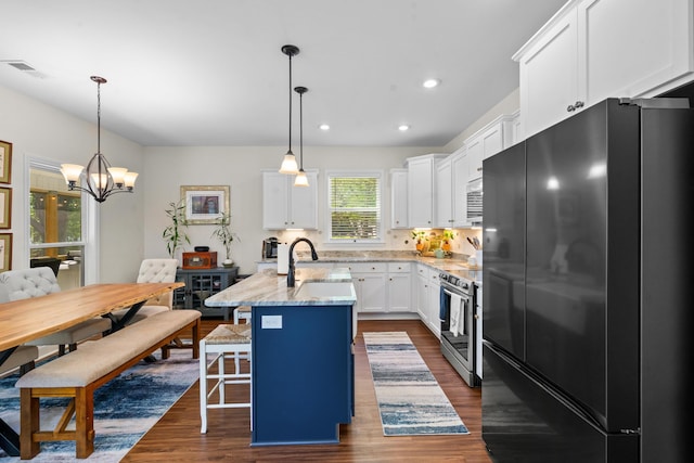 kitchen with visible vents, a sink, freestanding refrigerator, dark wood-style floors, and stainless steel electric range