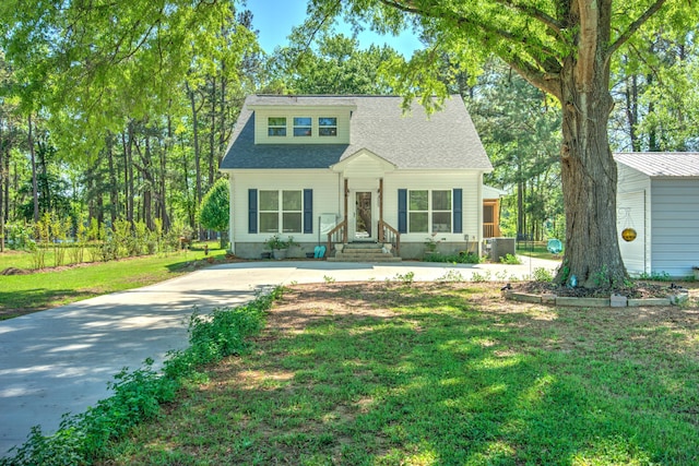 bungalow featuring central AC unit, roof with shingles, a front lawn, and concrete driveway
