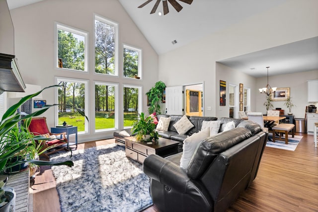 living area featuring visible vents, ceiling fan with notable chandelier, high vaulted ceiling, and wood finished floors