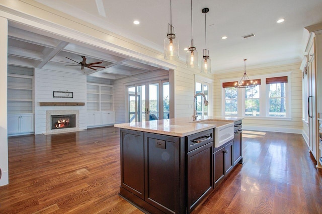 kitchen featuring a center island with sink, dark hardwood / wood-style flooring, light stone countertops, sink, and coffered ceiling