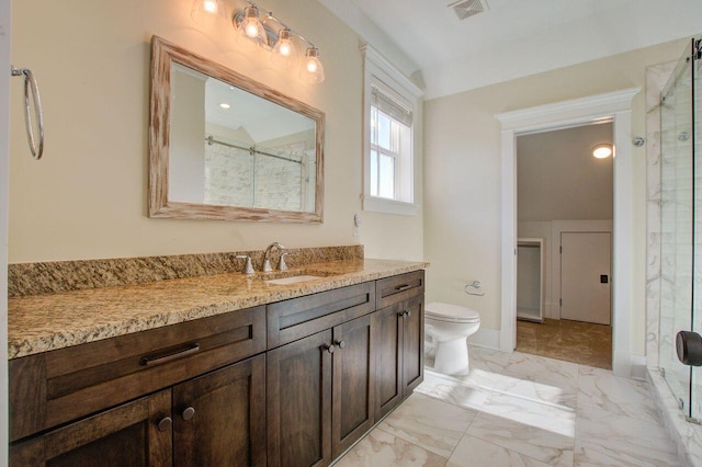 bathroom featuring toilet, vanity, and a shower with door