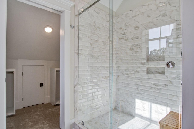 bathroom with a wealth of natural light, vaulted ceiling, and walk in shower