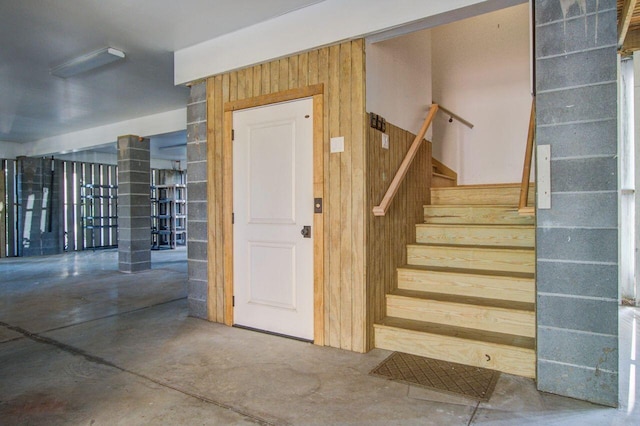 stairway featuring concrete floors and wood walls