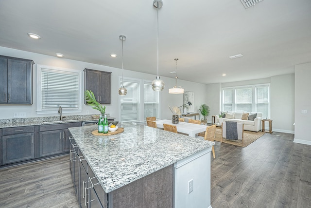 kitchen featuring a kitchen island, decorative light fixtures, sink, dark wood-type flooring, and a healthy amount of sunlight