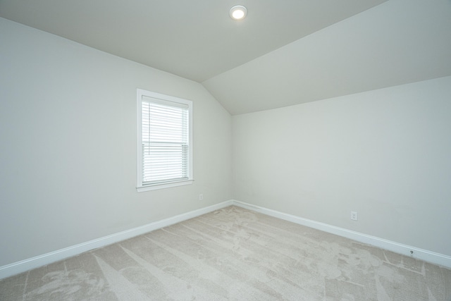 additional living space featuring lofted ceiling and light carpet