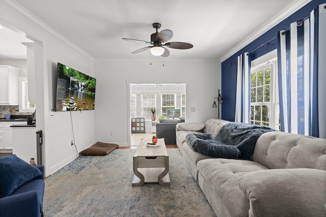 living room featuring baseboards, ornamental molding, and a ceiling fan