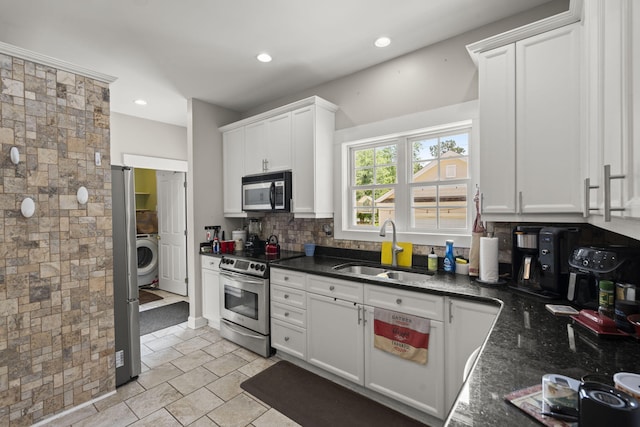 kitchen featuring decorative backsplash, washer / dryer, white cabinetry, a sink, and stainless steel appliances