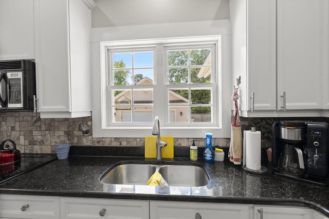kitchen featuring a sink, white cabinetry, dark stone countertops, and black appliances
