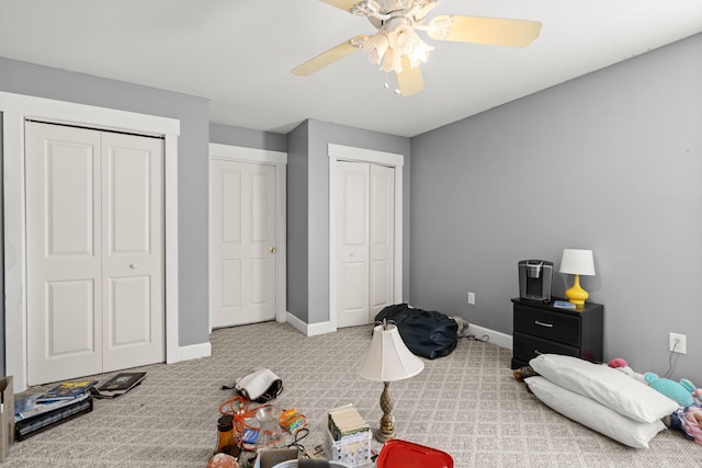 bedroom with carpet floors, multiple closets, ceiling fan, and baseboards