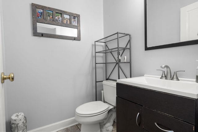 half bathroom with toilet, baseboards, and vanity