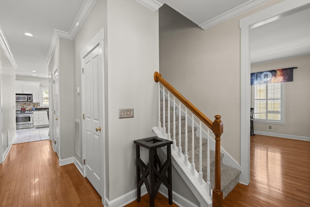 hall featuring baseboards, ornamental molding, light wood finished floors, and recessed lighting