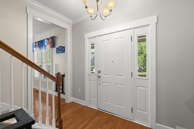 foyer featuring a healthy amount of sunlight, ornamental molding, wood finished floors, and a notable chandelier