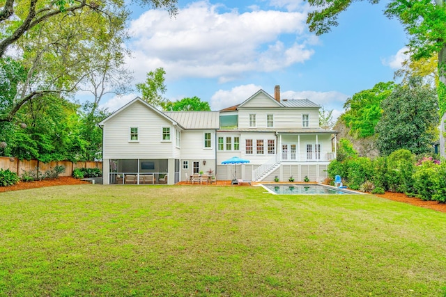 rear view of property with a lawn, a sunroom, and a deck