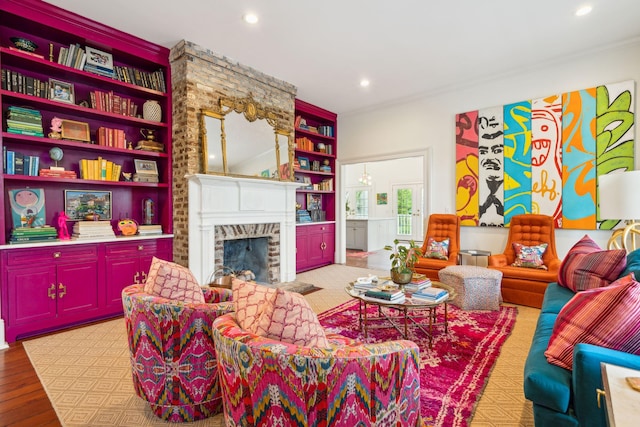 living room featuring built in shelves, light hardwood / wood-style floors, ornamental molding, and a brick fireplace