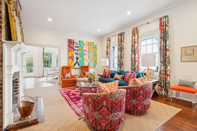 living room with a brick fireplace, plenty of natural light, and ornamental molding