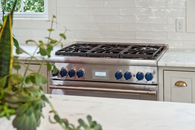 details with decorative backsplash, light stone countertops, and high end stainless steel range