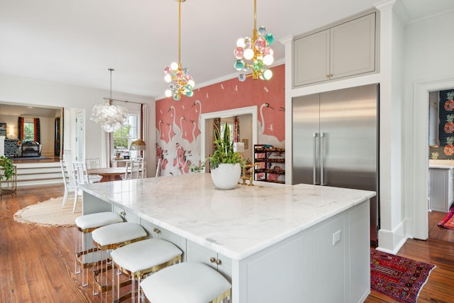 kitchen with light stone counters, pendant lighting, hardwood / wood-style flooring, an inviting chandelier, and a center island