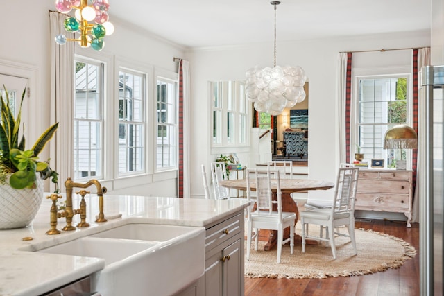 kitchen featuring sink, hanging light fixtures, dark hardwood / wood-style floors, crown molding, and a chandelier