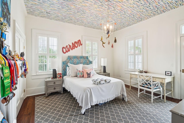 bedroom with dark hardwood / wood-style floors, an inviting chandelier, ornamental molding, and brick ceiling