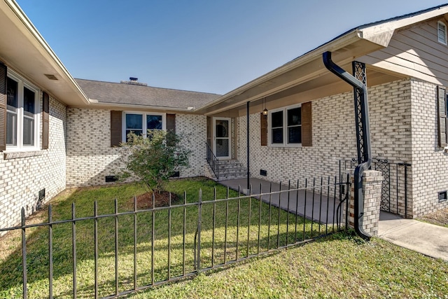 exterior space featuring a yard, fence, brick siding, and crawl space