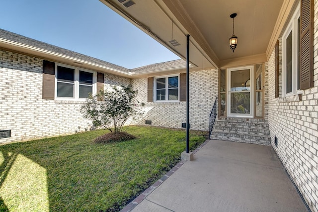 doorway to property with crawl space, a lawn, and brick siding