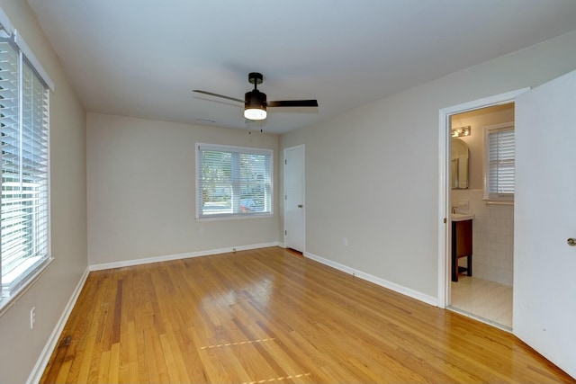 unfurnished bedroom featuring baseboards, ceiling fan, ensuite bathroom, and light wood finished floors