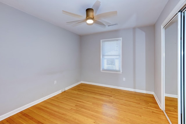 empty room featuring light wood finished floors, visible vents, a ceiling fan, and baseboards