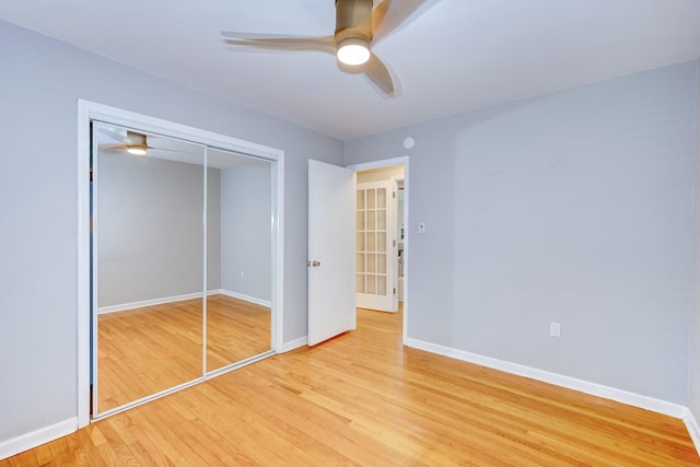 unfurnished bedroom featuring a ceiling fan, wood finished floors, baseboards, and a closet