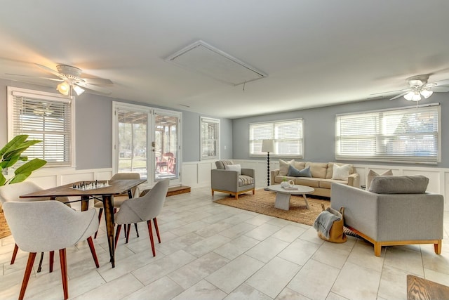 dining area with wainscoting, a decorative wall, light tile patterned floors, attic access, and ceiling fan