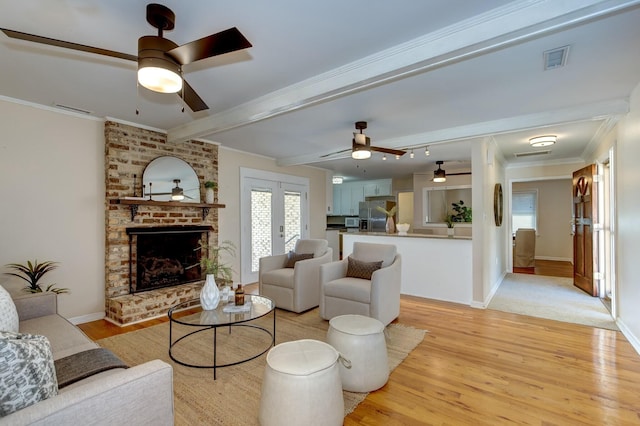 living room with light wood finished floors, visible vents, crown molding, and a ceiling fan