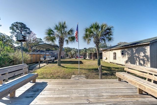 wooden deck featuring a detached carport and a lawn