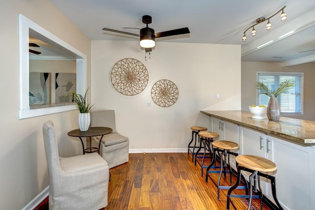 living area with visible vents, baseboards, wood finished floors, and a ceiling fan