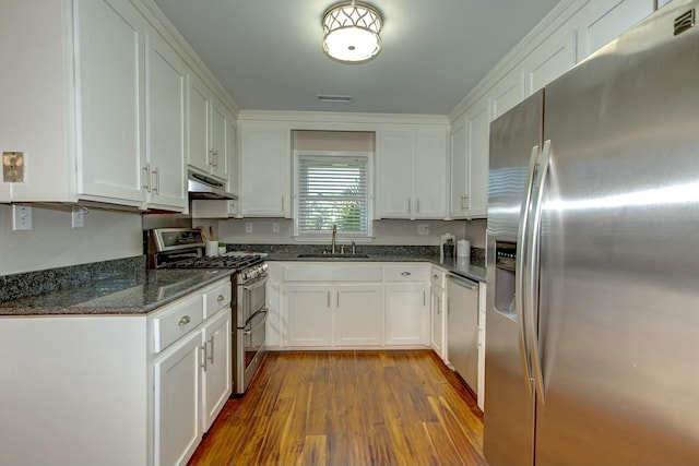 kitchen with under cabinet range hood, appliances with stainless steel finishes, wood finished floors, white cabinetry, and a sink