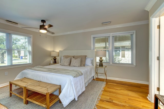 bedroom featuring visible vents, multiple windows, ornamental molding, and light wood finished floors