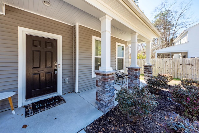 property entrance featuring covered porch and fence