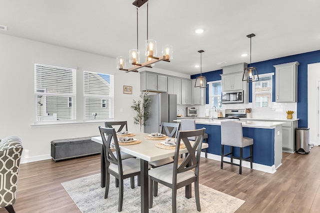 dining area with sink, an inviting chandelier, and hardwood / wood-style flooring