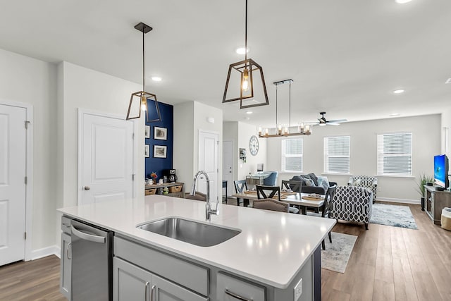 kitchen featuring sink, wood-type flooring, decorative light fixtures, a center island with sink, and ceiling fan with notable chandelier