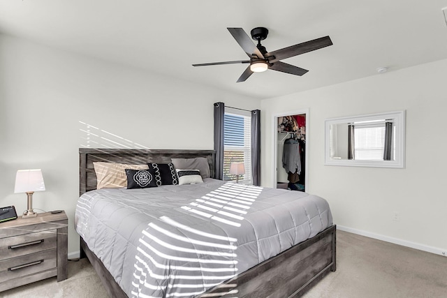 carpeted bedroom with ceiling fan, a walk in closet, and a closet