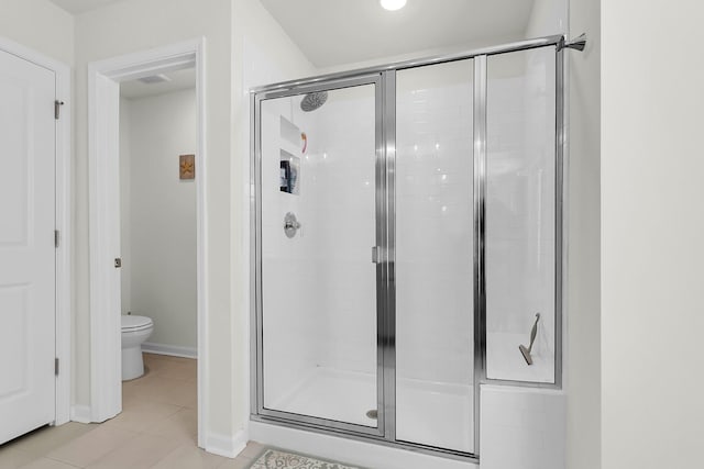 bathroom with tile patterned flooring, toilet, and a shower with door