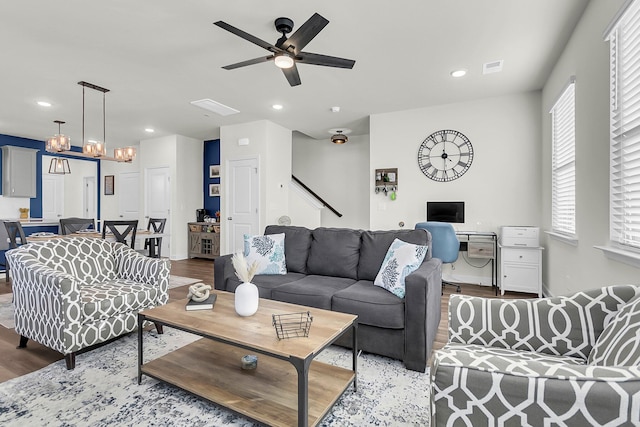 living room featuring ceiling fan with notable chandelier and hardwood / wood-style flooring